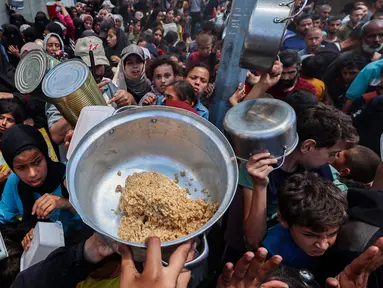 Warga Palestina berkumpul untuk menerima makanan hangat di titik distribusi makanan di kamp Nuseirat, Jalur Gaza Tengah pada 21 Mei 2025. (Eyad BABA/AFP)