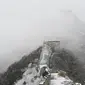 Tembok Besar China terlihat setelah hujan salju ringan di Jiankou, utara Beijing pada Minggu (9/1/2022). Jalur pada Tembok Besar China itu pun terlihat memutih akibat salju. (GREG BAKER / AFP)