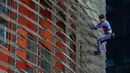 Pendaki pencakar langit, Alain Robert, yang juga dikenal sebagai 'Spiderman Prancis' memanjat Menara Agbar setinggi 144 meter di Barcelona, Rabu (4/3/2020). Aksi yang dilakukan tanpa menggunakan alat pengaman itu sebagai bentuk protes terhadap kepanikan atas epidemi virus corona. (LLUIS GENE/AFP)