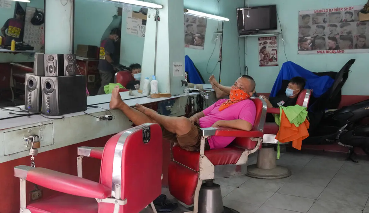 Tukang cukur menunggu pelanggan saat membuka kembali toko mereka setelah beberapa aktivitas bisnis diizinkan beroperasi kembali di Quezon, Filipina, Kamis (16/9/2021). Pemerintah memulai uji coba lockdown granular, di mana pembatasan ketat diterapkan untuk area yang lebih kecil. (AP/Aaron Favila)