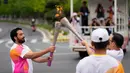 Seorang pembawa obor menyalakan api saat kirab obor Asian Games ke-19 di Hangzhou, China, Rabu, 20 September 2023. (AP Photo/Vincent Thian)