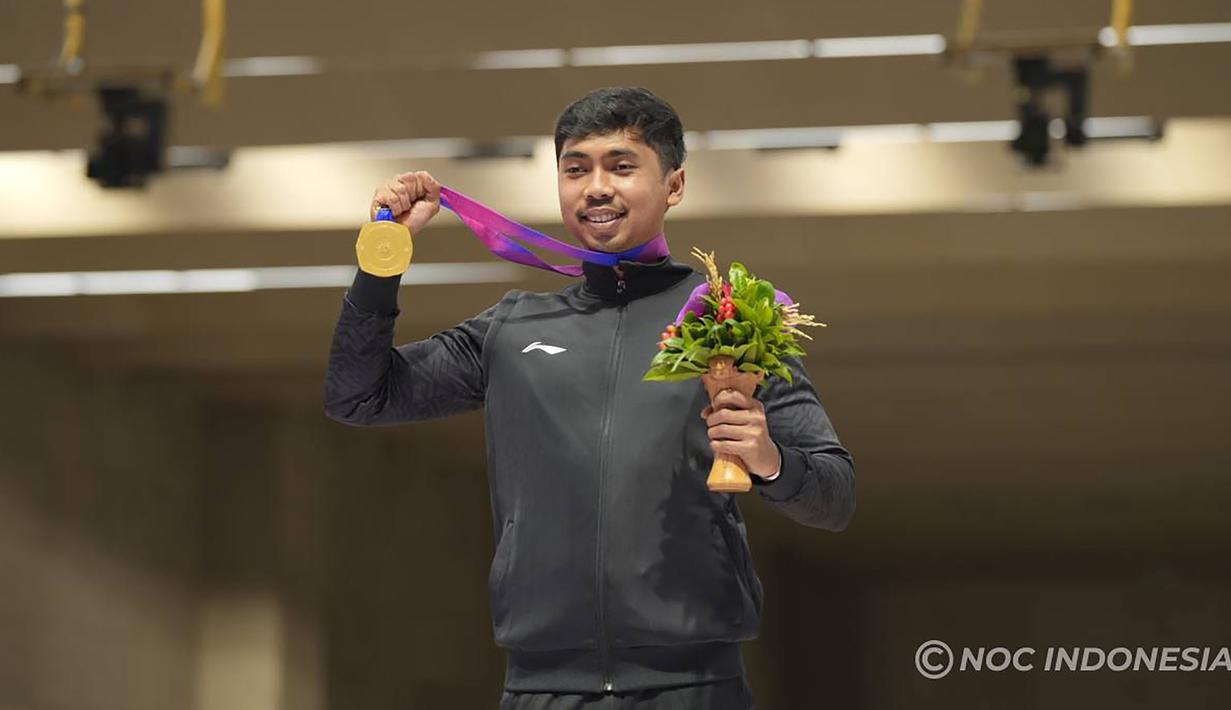 Selebrasi petembak Indonesia, Muhammad Sejahtera Dwi Putra dengan medali emas di atas podium usai memenangi lomba nomor perorangan 10 meter running target putra cabang menembak Asian Games Hangzhou 2022 di Fuyang Yinhu Sports Centre, Hangzhou, China, Senin (25/9/2023). (NOC Indonesia)