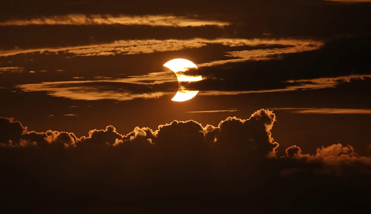 Gerhana matahari sebagian muncul di balik awan, Arbutus, Md, Kamis (10/6/2021).  (AP Photo/Julio Cortez)