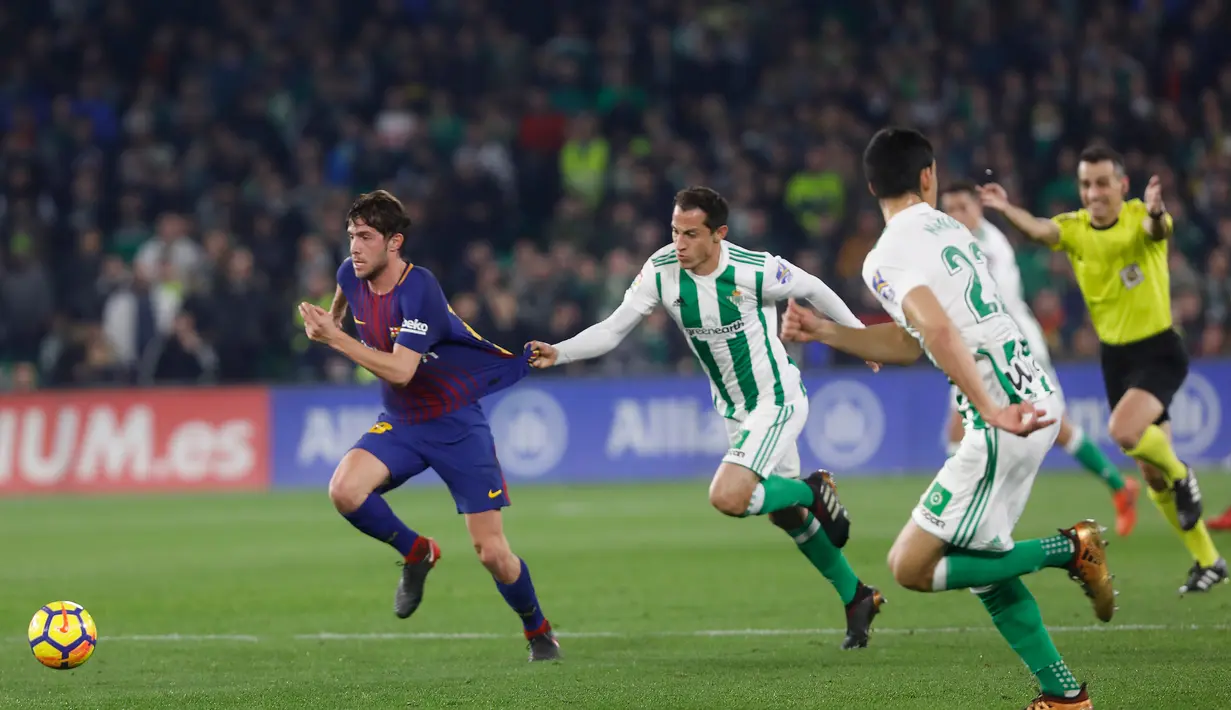 Pemain Barcelona, Sergi Roberto berusaha mengendalikan bola dengan kawalan pemain Real Betis, Guardado pada pertandingan lanjutan La Liga di Stadion Benito Villamarin, Minggu (21/1). Barcelona menyegel kemenangan dengan skor 5-0. (AP/Miguel Morenatti)