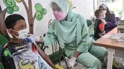 Petugas puskesmas menenangkan seorang anak sebelum disuntik vaksin DT di RPTRA Citra Permata, Jakarta, Selasa (28/9/2021). Kegiatan rutin tahunan tersebut bertujuan memberikan kekebalan tubuh pada anak sekolah terhadap penyakit DT dengan kuota 150 anak per hari. (merdeka.com/Iqbal S Nugroho)