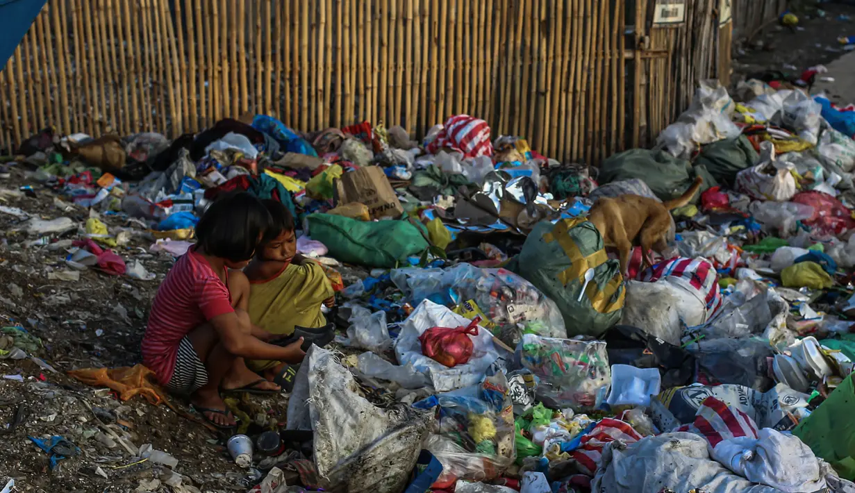 Dua orang anak melihat sepatu saat menyortir sampah di permukiman kumuh di sepanjang garis pantai Pantai Baseco di Manila (28/9/2019). Daerah ini rawan banjir akibat angin topan dan hujan lebat. (AFP Photo/Maria Tan)