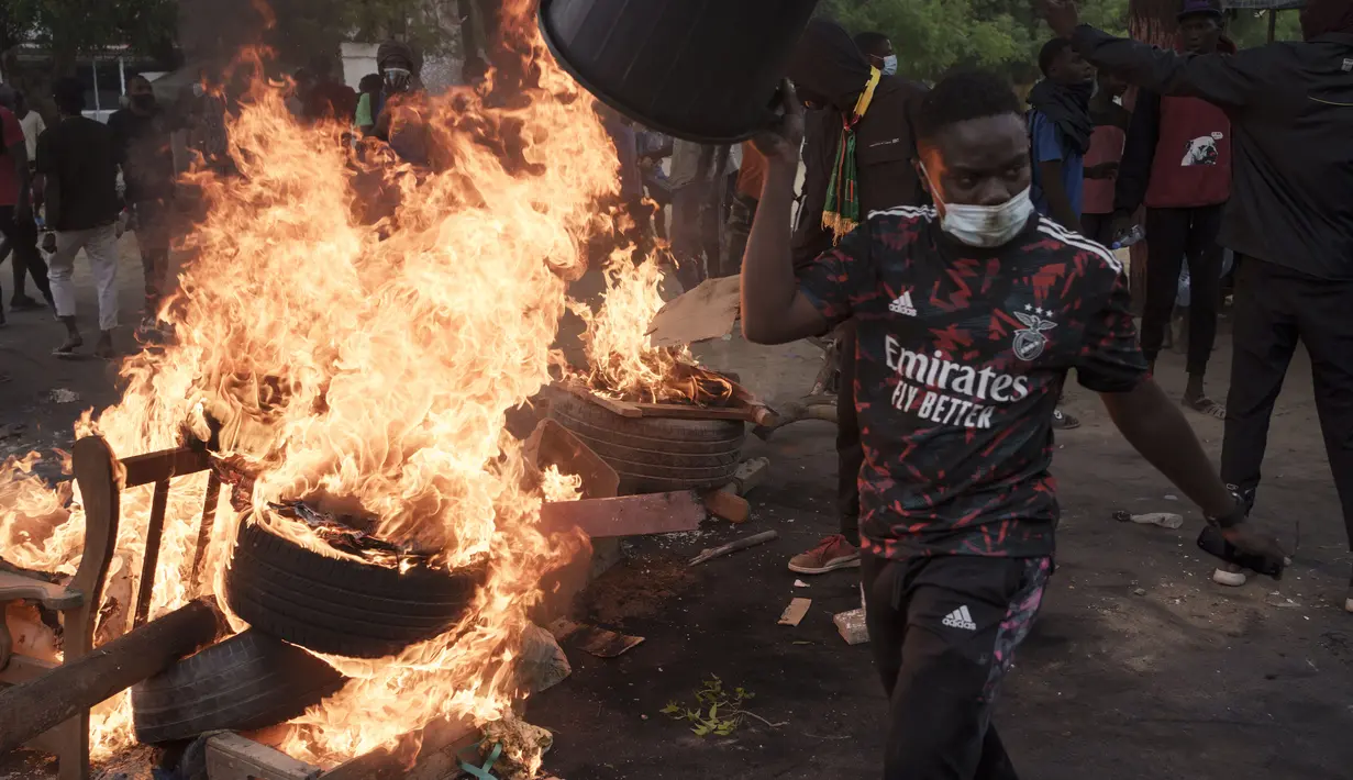 Seorang demonstran berjalan melewati barikade yang dibakar selama protes untuk mendukung pemimpin oposisi utama Ousmane Sonko di Dakar, Senegal, Senin (29/5/2023). (AP Photo/Leo Correa)