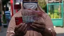 Warga menunjukkan uang usai melakukan penarikan bantuan sosial tunai (BST) di ATM Bank DKI di Jakarta, Selasa (20/7/2021). BST sebesar Rp 600 ribu bagi warga DKI Jakarta yang terdampak pandemi COVID-19 langsung masuk ke rekening masing-masing penerima. (Liputan6.com/Angga Yuniar)