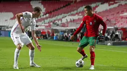 Striker Portugal, Cristiano Ronaldo, berusaha melewati bek Prancis, Benjamin Pavard, pada laga UEFA Nations League di Stadion Da Luz, Minggu (15/11/2020). Prancis menang dengan skor 1-0. (AP/Armando Franca)