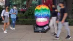 Orang-orang melewati tengkorak yang dihias selama pameran edisi keempat "Mexicraneos" (Mexisculls) di Reforma Avenue, Mexico City pada 23 Oktober 2020. Instalasi sebanyak 55 tengkorak berbagai warna tersebut menghiasi jalanan sebagai bagian dari perayaan Day of the Dead. (ALFREDO ESTRELLA/AFP)