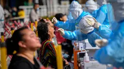 Petugas medis mengambil sampel warga saat tes COVID-19 di Qingdao, China, Senin (12/10/2020). Lebih dari 9 juta orang yang tinggal di kota Qingdao menjalani tes COVID-19 secara massal setelah kasus baru muncul terkait dengan rumah sakit yang merawat pasien terinfeksi dari luar negeri. (STR/AFP)