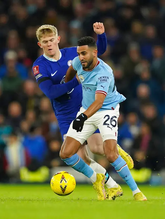 Pemain Manchester City Riyad Mahrez (kanan) berebut bola dengan pemain Chelsea Lewis Hall pada pertandingan sepak bola Piala FA di Etihad Stadium, Manchester, Inggris, 8 Januari 2023. Manchester City mengalahkan Chelsea dengan skor 4-0. (AP Photo/Dave Thompson)