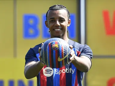 Bek baru Barcelona dari Prancis Jules Kounde berpose saat upacara presentasi di tempat latihan Joan Gamper di Sant Joan Despi, Barcelona (1/8/2022). Jules Kounde resmi diperkenalkan sebagai pemain baru Barcelona. Kounde jadi rekrutan kelima Barca di bursa transfer musim ini. (AFP/Pau Barrena)