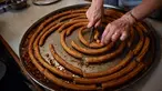 Seorang wanita menyiapkan potongan churros di toko churreria kuno yang didirikan pada tahun 1872 di Pamplona, Spanyol, Senin (10/7/2023). Churros merupakan sarapan khas selama berlangsungnya Festival San Fermin. (AP Photo/Alvaro Barrientos)