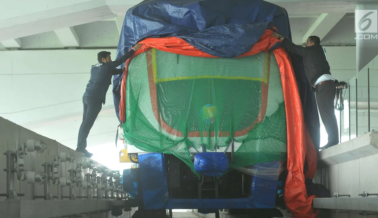 Pekerja membuka selubung skytrain yang baru dipasang di Terminal 3 Bandara Soekarno Hatta, Tangerang, Selasa (30/5). Kereta tanpa awak ini rencananya akan diuji coba mengangkut penumpang antara terminal 2 dan terminal 3. (Liputan6.com/Helmi Afandi)