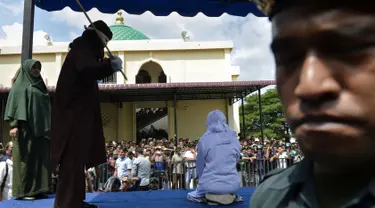 Seorang wanita berusia 19 tahun menjalani hukuman cambuk di depan umum di Banda Aceh (31/1). Dua remaja AS laki-laki (19) dan NS perempuan (19) dicambuk setelah mereka ketahuan berpelukan di depan umum. (AFP Photo/Chaideer Mahyudin)