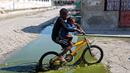 Dua anak melewati genangan air limbah saat naik sepeda melewati daerah Cite Soleil di Port-au-Prince, Haiti (17/3). Cite Soleil awalnya dikembangkan sebagai kota kumuh dan tumbuh hingga sekitar 200.000 hingga 400.000 penduduk. (AP Photo/Dieu Nalio Chery)