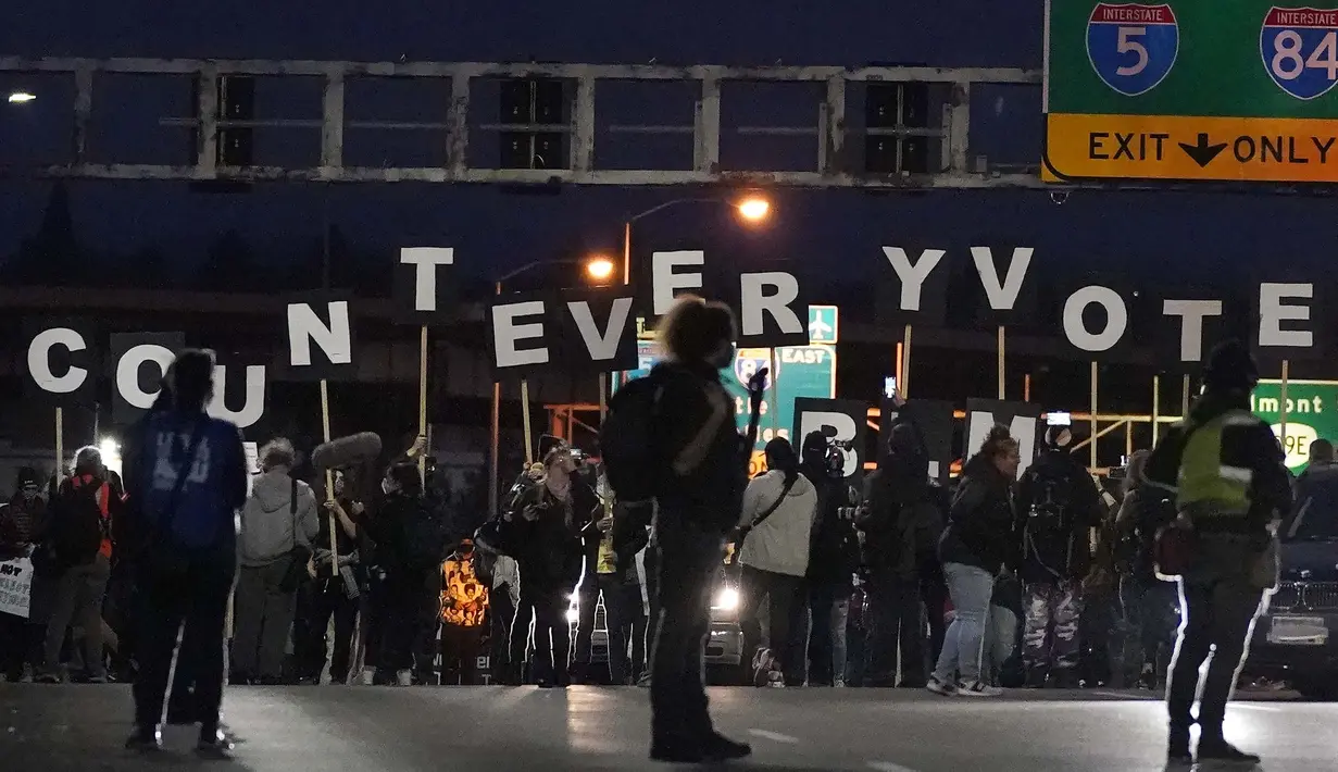 Para pengunjuk rasa memegang surat yang berbunyi "Hitung Setiap Suara" saat mereka melewati jembatan penyeberangan setelah pemilihan presiden di Portland, Oregon, Amerika Serikat, Rabu (4/11/2020). (AP Photo/ Marcio Jose Sanchez)