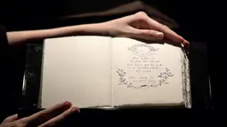Pekerja memperlihatkan satu dari tujuh eksemplar buku tulisan tangan dan digambar oleh J.K. Rowling di rumah lelang Sotheby, London, 9 Desember 2016. Buku 'The Tales of Beedle the Bard' itu terjual USD467 ribu atau sekitar Rp6,2 miliar (Justin TALLIS/AFP)