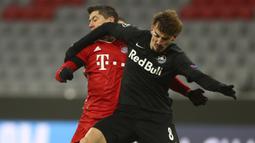 Penyerang Bayern Munchen, Robert Lewandowski, berebut bola dengan penyerang RB Salzburg, Mergim Berisha, pada laga lanjutan Grup A Liga Champions di Allianz Arena, Kamis (26/11/2020) dini hari WIB. Bayern Munchen menang 3-1 atas RB Salzburg. (AP Photo/Matthias Schrader)