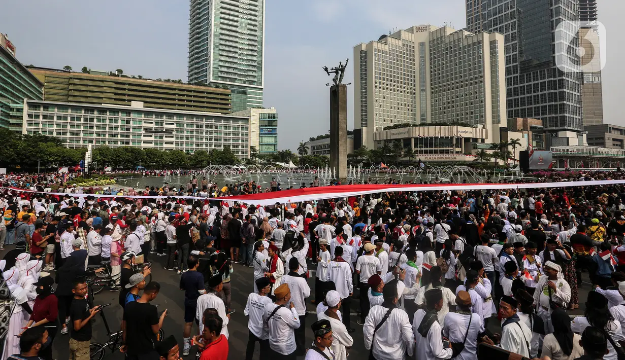 Sejumlah peserta membentangkan Bendera Merah Putih di kawasan Thamrin, Jakarta, Minggu (28/8/2022). Sebanyak 50.000 orang membentangkan bendera merah putih sepanjang 1.700 meter dari kawasan Monas hingga Bundaran Hotel Indonesia dalam rangka memperingati HUT ke-77 Kemerdekaan Republik Indonesia bertemakan 'Pulih Lebih Cepat, Bangkit Lebih Kuat. (Liputan6.com/Johan Tallo)