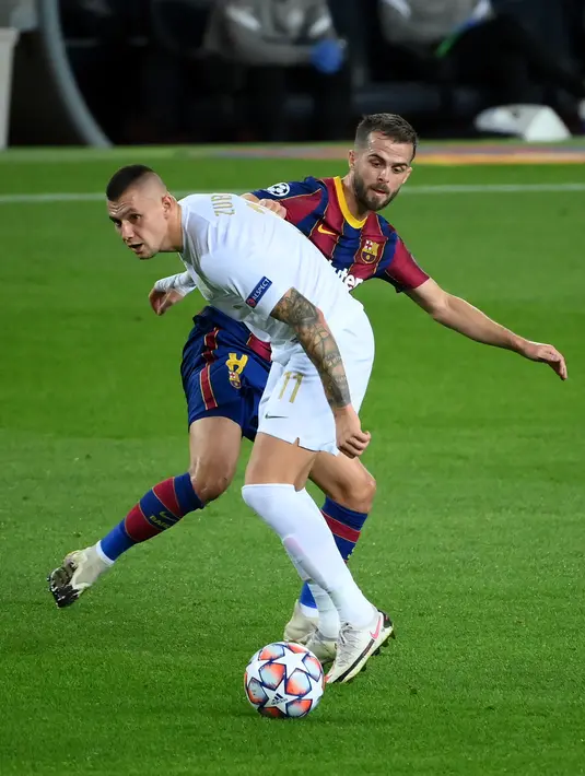 Gelandang Barcelona, Miralem Pjanic (kanan) berebut bola dengan gelandang Ferencvaros, Oleksandr Zubkov pada laga pertama Grup G Liga Champions 2020-2021 di Camp Nou, Rabu (21/10/2020) dini hari WIB. Main dengan 10 pemain, Barcelona mampu mencukur Ferencvaros 5-1. (LLUIS GENE / AFP)