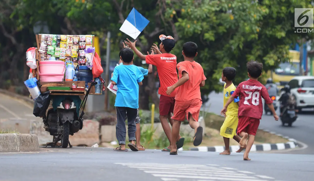 Anak-anak mengejar layang-layang yang putus di tepi Kanal Banjir Timur (KBT), Jakarta, Jumat (5/7/2019). Layang-layang sangat diminati berbagai kalangan dari anak-anak hingga orang dewasa. (merdeka.com/Imam Buhori)