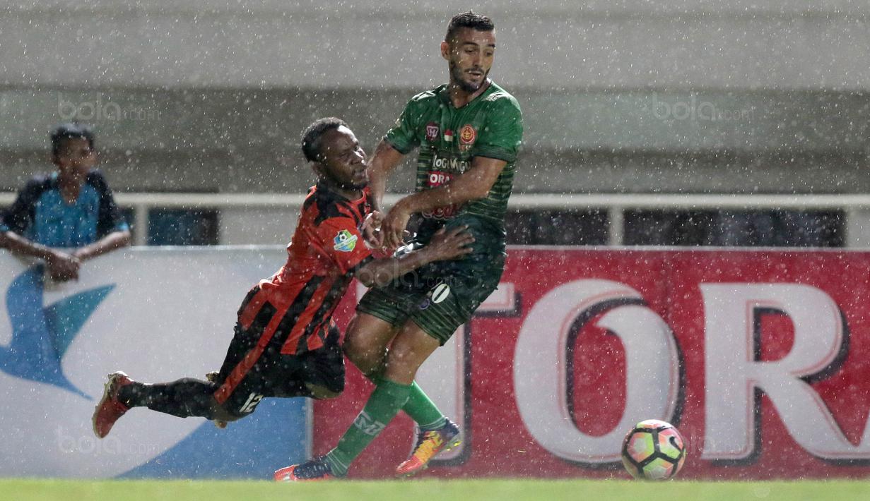 Pemain PS TNI, Redouane Zerzouri (kanan) berebut bola dengan pemain Perseru Serui, Lucas Mandowen pada lanjutan Liga 1 2017 di Stadion Pakansari, Bogor (07/10/2017). PS TNI menang 2-1. (Bola.com/Nicklas Hanoatubun)