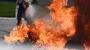Seorang petugas trek mencoba memadamkan sepeda motor yang terbakar menyusul kecelakaan yang melibatkan pembalap Aprilia Gresini, Lorenzo Savadori dan pembalap KTM, Dani Pedrosa saat balapan MotoGP Styria 2021 di Red Bull Ring, Minggu (8/8/2021). (JOE KLAMAR/AFP)