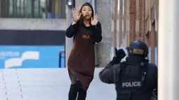Salah seorang sandera wanita lari dari Kafe Lindt, Martin Place, Sydney, ke arah petugas polisi bersenjata, Senin (15/12/2014). (REUTERS/Jason Reed)