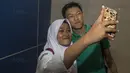 Gelandang Timnas Indonesia U-19, Feby Eka Putra, selfie bersama fans usai latihan di Stadion Wibawa Mukti, Bekasi, Senin (16/10//2017). Kehadiran fans dengan senang hati disambut pemain Timnas U-19. (Bola.com/Vitalis Yogi Trisna)