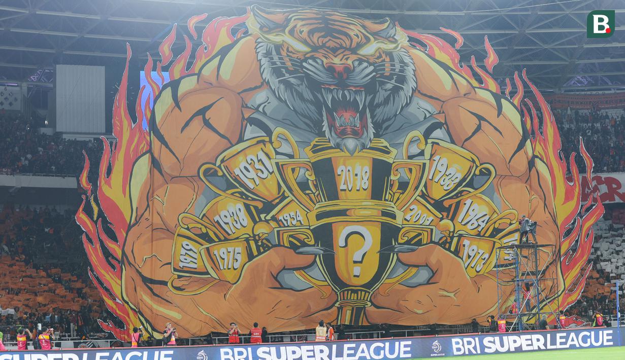 The Jakmania membentangkan koreografi raksasa Macan memeluk trofi saat laga Persija Jakarta  vs PSIM Yogyakarta pada laga pekan ke-14 BRI Super League 2025/2026 di Stadion Utama Gelora Bung Karno, Jakarta, Jumat (28/11/2025) malam. (Bola.com/M Iqbal Ichsan).