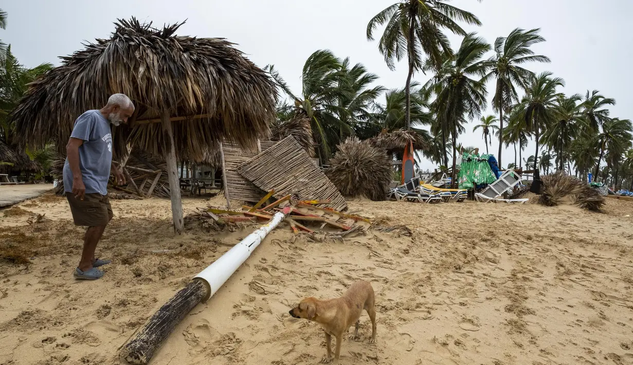Seorang pedagang bekerja di tengah puing-puing usaha kecilnya berupa penyewaan payung dan makanan setelah diterjang Badai Fiona di pantai di Punta Cana, Republik Dominika (19/9/2022). Badai Fiona datang dengan membawa hujan lebat dan angin kencang di Republik Dominika. (AP Photo/Ricardo Hernandez)