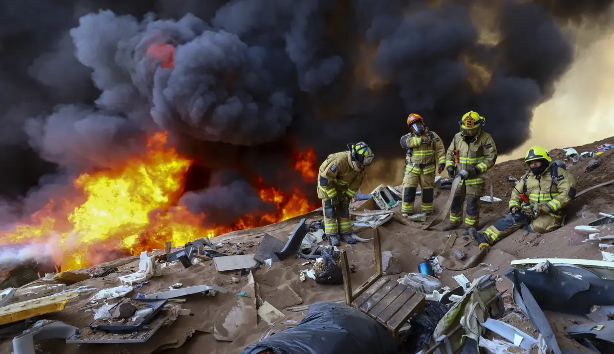 Petugas pemadam kebakaran menunggu air saat kebakaran di lingkungan berpenghasilan rendah Laguna Verde, di Iquique, Chili, Senin (10/1/2022). Menurut pihak berwenang, api menghanguskan hampir 100 rumah di lingkungan itu yang sebagian besar dihuni oleh para migran. (AP Photo/Ignacio Munoz)