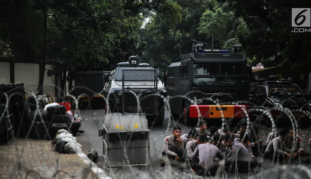 Petugas berjaga dibalik kawat berduri yang dipasang didepan Kedutaan Besar Myanmar, Jakarta, Rabu (6/9).  Jelang aksi yang rencananya akan dihadiri puluhan ribu orang, pihak kepolisian berjaga di sekitar Kedubes Myanmar. (Liputan6.com/Faizal Fanani)