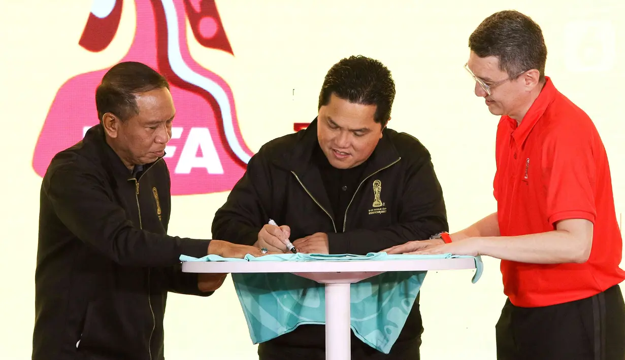 <p>Ketua Umum PSSI Erick Thohir (tengah) disaksikan Menpora Zainudin Amali (kiri) saat menandatangani jersey pada launching merchandise resmi Piala Dunia U-20 2023 di Atrium Mall FX Sudirman, Senayan, Jakarta, Rabu (8/3/2023). Apparel lokal, Juara, dipercaya menjadi penyedia suvenir Piala Dunia U-20 2023 dengan menyediakan 53 jenis merchandise yang siap dijual ke masyarakat. (Liputan6.com/Herman Zakharia)</p>