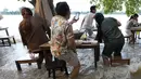 Pelanggan Chaopraya Antique Café di tepi sungai menikmati ketinggian air di Sungai Chao Phraya dekat Bangkok, Thailand, Kamis (7/10/2021). Karena kebanjiran, alih-alih kursi kosong dan meja kosong justru restoran penuh seperti biasanya bagi para pencinta santapan 'hot-pot'. (AP Photo/Sakchai Lalit)