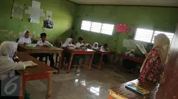 Suasana belajar mengajar di MI Mansyaul Huda yang terkena dampak abrasi di pantai Muara Gembong, Bekasi, Selasa, (26/7). Tingkat abrasi yang tinggi menyebabkan sejumlah rumah terkikis dan beberapa sekolah terendam air laut. (Liputan6.com/Gempur M Surya)