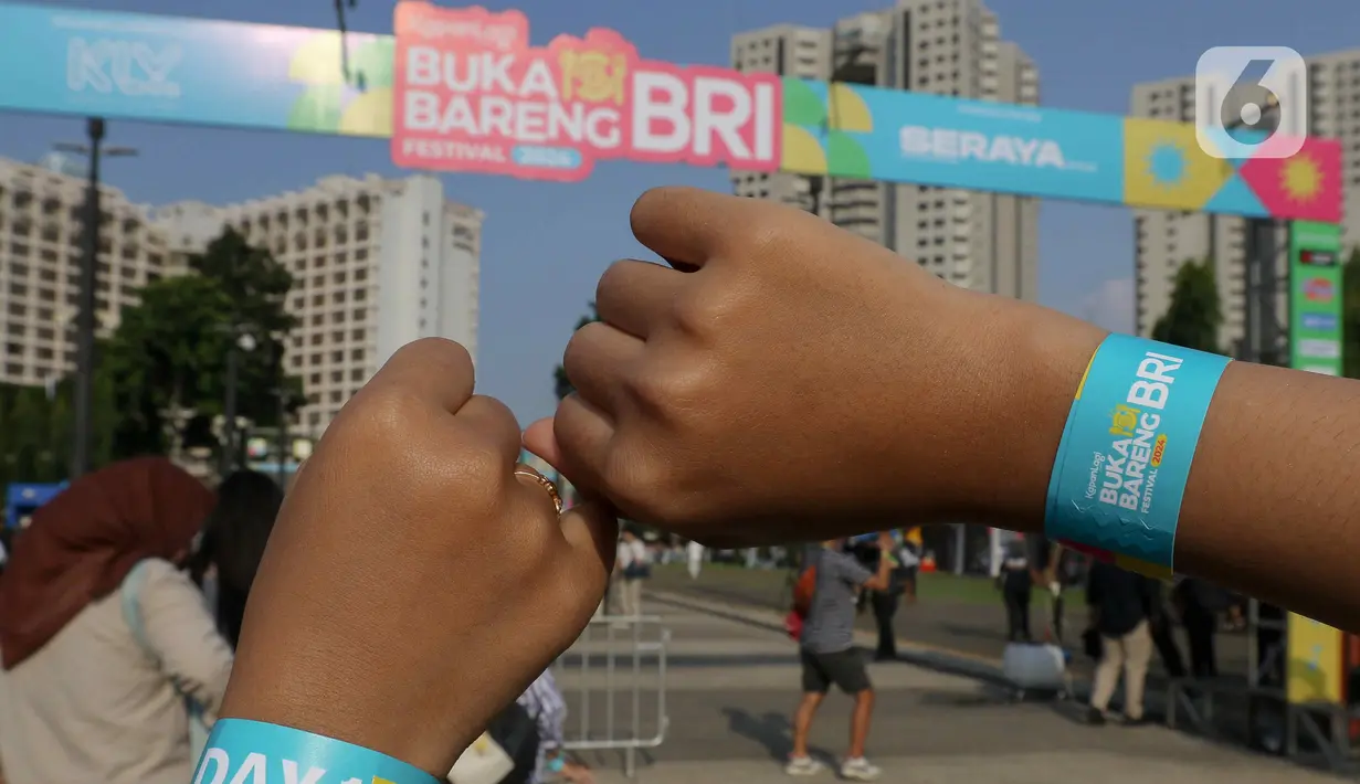 Pengunjung memperlihatkan gelang tangan KapanLagi Buka Bareng BRI Festival 2024 di Plaza Timur Senayan, Jakarta, Sabtu (23/3/2024). (Liputan6.com/Herman Zakharia)