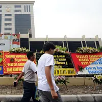 Warga melintasi deretan karangan bunga yang diletakkan di depan Mabes Polri, Jakarta, Rabu (3/5). Ratusan karangan bunga itu terus berdatangan dan mengelilingi gedung Mabes Polri di Jalan Trunojoyo Jakarta Selatan. (Liputan6.com/Helmi Fithriansyah)