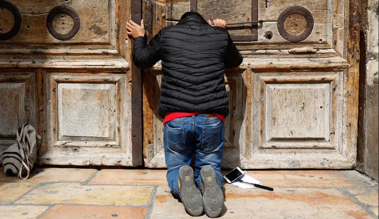 Seorang peziarah berdoa di gerbang Gereja Makam Kudus di Kota Tua Yerusalem, Minggu (25/2). Para pemimpin Kristen mengambil langkah langka untuk menutup gereja yang menjadi tempat di mana Yesus disalibkan, wafat, dimakamkan, dan bangkit. (GALI TIBBON/AFP)