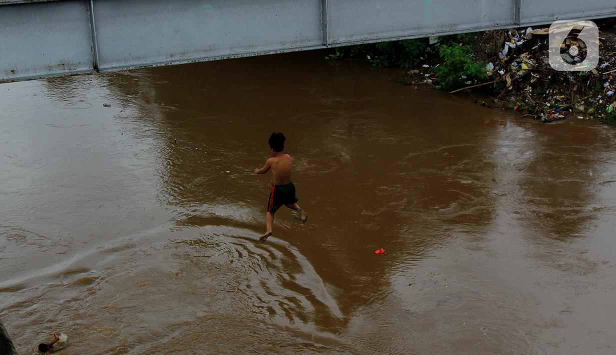 Seorang anak nekat melompat dari jembatan ke Kali Ciliwung Kalibata, Jakarta, Selasa (25/2/2020). Kali Ciliwung meluap usai hujan deras mengguyur Jakarta dan sekitarnya pada kemarin malam. (merdeka.com/magang/Muhammad Fayyadh)