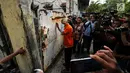 Tersangka penampung TKI Ilegal bersiap masuk ke dalam rumah di Jalan Percetakan Negara X, Jakarta, Rabu (31/5). Bersama satu tersangka, petugas Dirtipidum Mabes Polri melakukan pencarian barang bukti baru. (Liputan6.com/Helmi Fithriansyah)