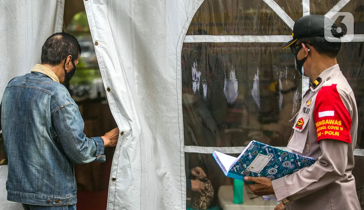 Polisi berjalan saat warga memasuki ruangan untuk mengikuti rapid test gratis di Pos Pengamanan Natal 2020 dan Tahun Baru 2021 Polsek Kebayoran Lama, Jakarta, Selasa (29/12/2020). Rapid test itu dilakukan untuk membantu mengurai antrean warga saat tes di tempat lainnya. (Liputan6.com/Faizal Fanani)