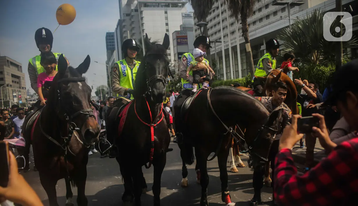 Sejumlah anak berfoto dengan polisi berkuda dari Direktorat Polisi Satwa Mabes Polri di kawasan Bundaran HI, Jakarta, Minggu (17/11/2019). Polisi berkuda tersebut khusus ditugaskan mengawasi keamanan CFD serta memperkenalkan kepada warga. (Liputan6.com/Faizal Fanani)