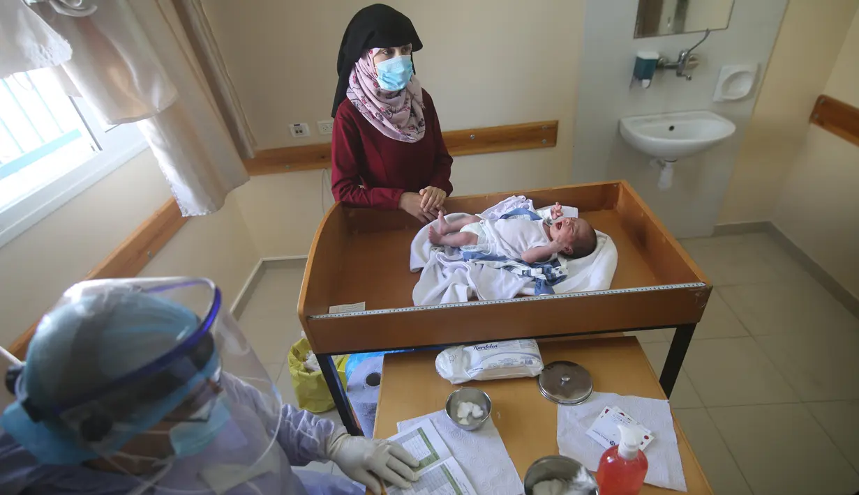 Seorang wanita Palestina menunggu bayinya divaksinasi di sebuah pusat layanan kesehatan saat pemberlakuan lockdown, Kota Rafah, Jalur Gaza, 9 September 2020. (Xinhua/Khaled Omar)
