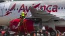 Pekerja menutupi bagian-bagian motor pesawat dengan plastik untuk mencegah abu vulkanik masuk di bandara internasional La Aurora yang telah ditutup akibat letusan di gunung berapi Pacaya di Guatemala City (23/3/2021). (AP Photo / Moises Castillo )