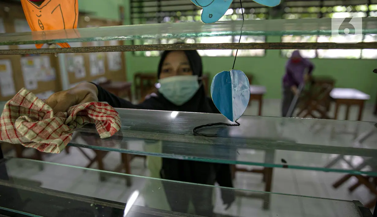 Sejumlah guru membersihkan kelas yang akan digunakan di SDN Kenari 08, Jakarta, Selasa (6/4/2021). Pemerintah Provinsi DKI Jakarta akan melakukan uji coba pembelajaran tatap muka terbatas di 100 sekolah mulai 7 April hingga 29 April 2021. (Liputan6.com/Faizal Fanani)