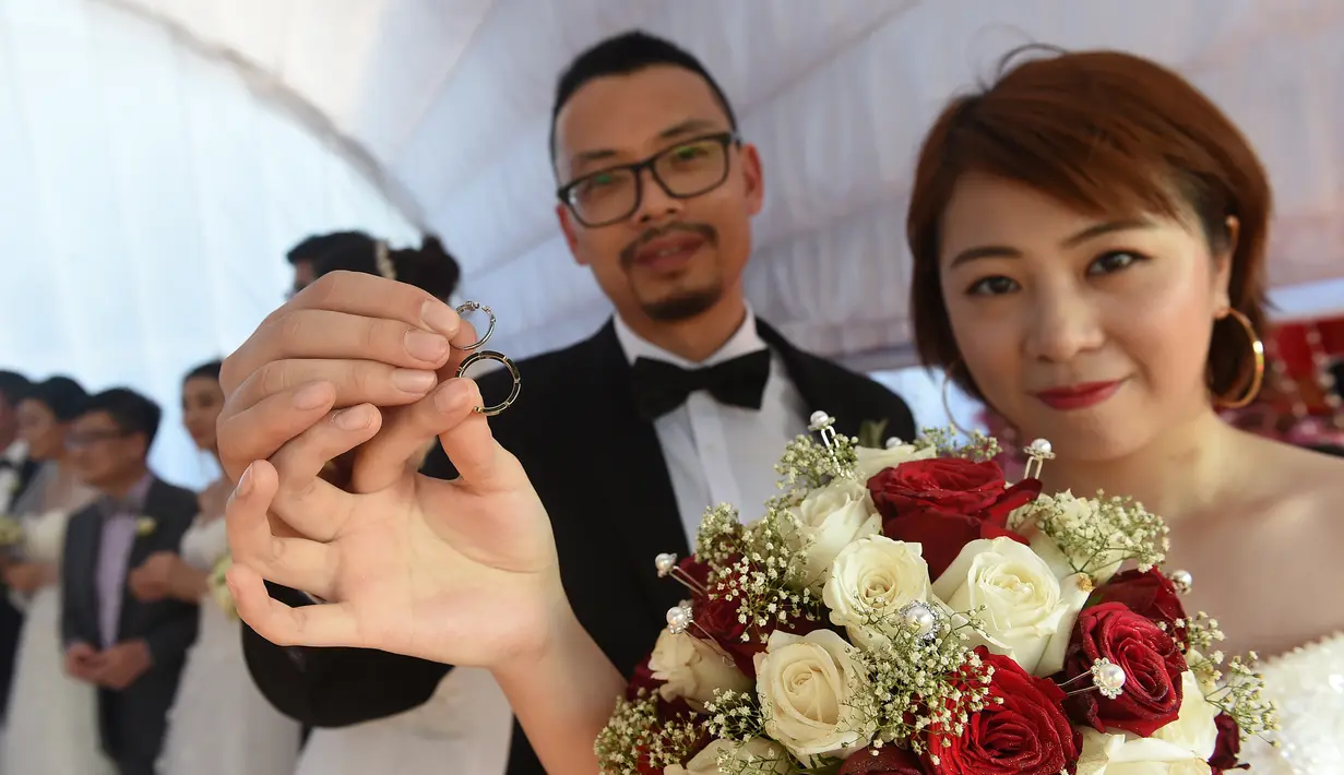 Pasangan pengantin asal Tiongkok menunjukkan cincin kawin saat mengikuti pernikahan massal di Kolombo, Sri Lanka (17/12). Acara nikah massal ini bertujuan untuk meningkatkan pariwisata di Sri Lanka (AFP Photo/Ishara S. Kodikara)