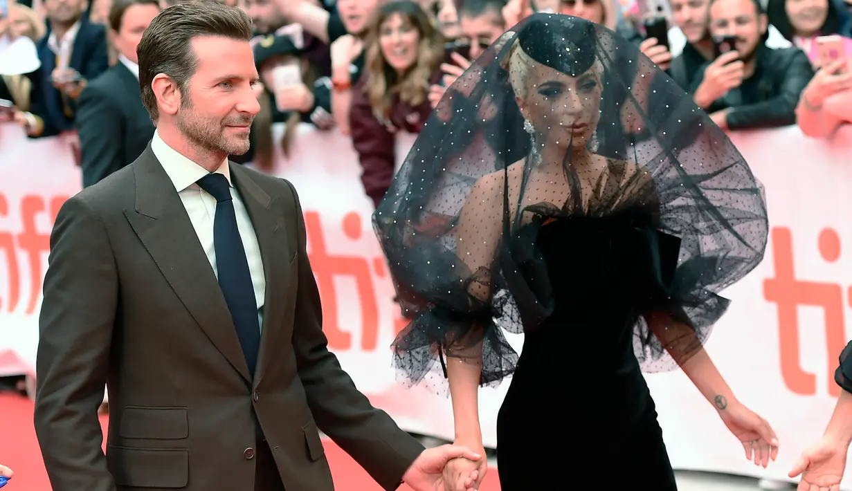 Lady Gaga dan Bradley Cooper tiba di karpet merah menghadiri pemutaran film "A Star is Born" selama Toronto International Film Festival 2018 di Toronto (9/9). Lady gaga tampil menggenakan gaun berwarna hitam. (AP Photo/Nathan Denette)